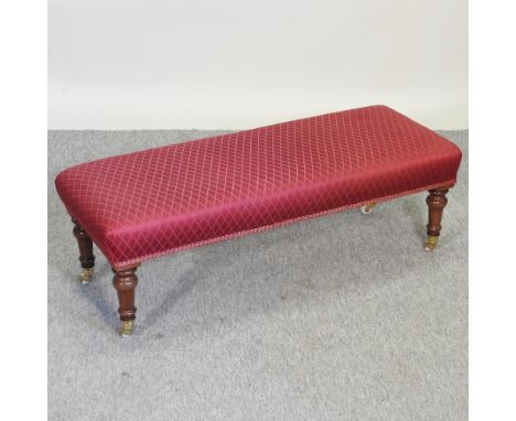 A Victorian style red upholstered mahogany footstool, on turned legs and ceramic castors, 94cm
