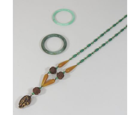 An oriental jade coloured hardstone bangle, together with another and an Eastern bead necklace, with carved beads