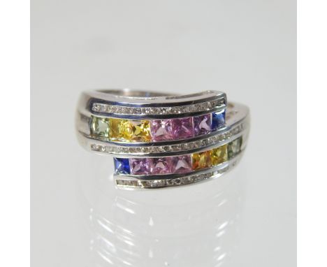 A modern 9 carat gold, sapphire multi gem set dress ring, of crossover design, size R, 6.5g gross, boxed