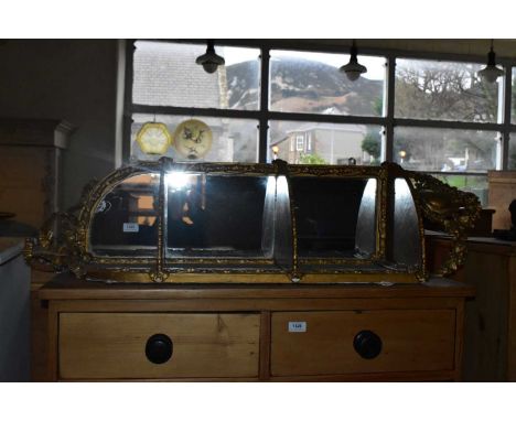 An early 20th century gilt painted corner shelf with mirrored back and scrolling detail, length 100cm.