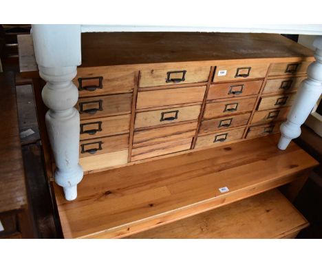 A vintage pine haberdashery type chest with an arrangement of twenty drawers, width 127cm, depth 32cm, height 44cm.