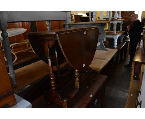 A reproduction oak drop-leaf gateleg dining table on bun feet, height 72cm, length 81cm.