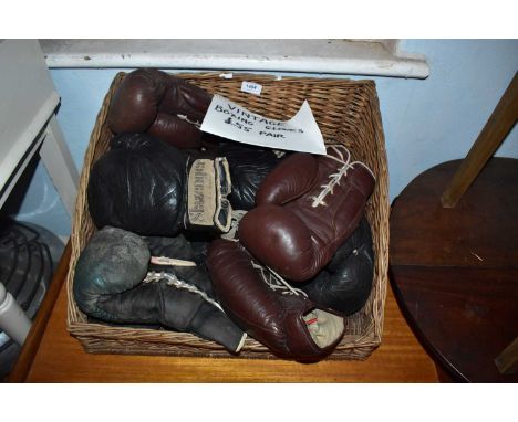 A vintage wicker basket containing a quantity of vintage boxing gloves.