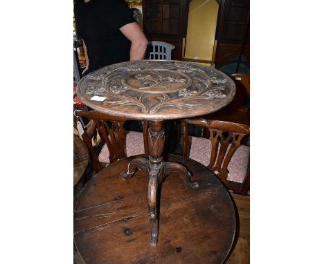 A Black Forest carved wood tripod table with relief floral decoration, height 62cm, diameter 59cm.