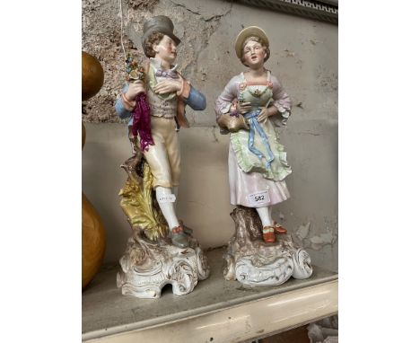 A pair of continental ceramic figures - gentleman carrying bunch of flowers tied with ribbons, and lady carrying basket of fl