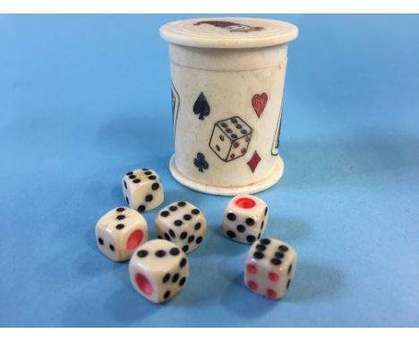 A small early 20th century bone container decorated with dice and playing cards, containing six small dice.  4cm high