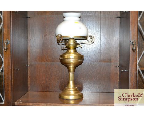 A brass oil lamp with opaque glass shade