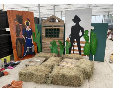 A COLLECTION OF STAGE PROPS FOR A COUNTRY AND WESTERN SCENE TO INCLUDE JAIL HOUSE, CUT OUT HEAD SCENE AND HAY BALES ETC 