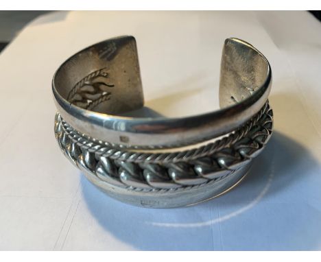 A LARGE HEAVY SILVER BANGLE WITH ROPE DESIGN 