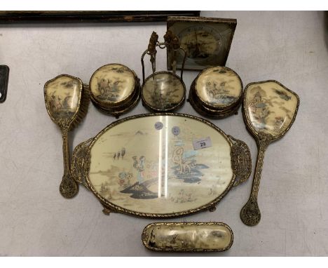 AN EIGHT PIECE ORNATE GILT DRESSING TABLE SET COMPRISING TRAY, HAND HELD MIRROR, BRUSHES, TRINKET DISHES, CLOCK ETC. DEPICTIN