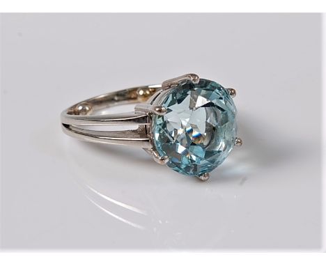 A single stone aquamarine ring, the round aquamarine, approx. 11.4mm diameter, in a six claw mount, bifurcated shoulders and 