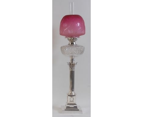 A circa 1900 silver plated Corinthian column pedestal oil lamp, having cranberry tinted dome shade, star cut font to a fluted