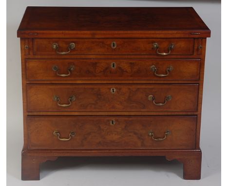 A walnut bachelors chest, in the George II style, the quarter veneered and feather strung rectangular fold-over top above an 