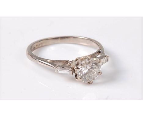 A diamond ring, the central round brilliant cut diamond, estimated approx. 0.94cts, set to either side with a single bagette 