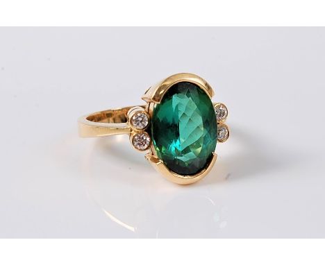 A green tourmaline and diamond dress ring, the oval green tourmaline approx. 12.9 x 9.6mm, in a half collet mount, set to eit
