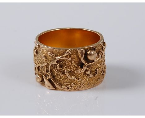 A 9ct artisan ring, the 11.9mm wide band, with abstract naturalistic decoration, hallmarked London 1976, size J-K, (8.4g)   C