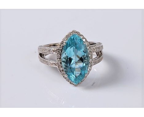 An 18ct aquamarine and diamond ring, the marquise cut aquamarine, approx. 15.5 x 8.8mm, in a four claw mount, surrounded by a