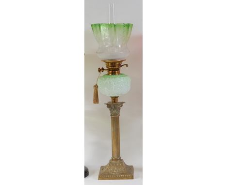 A late Victorian embossed brass pedestal oil lamp, having green tinted acid etched shade and moulded green glass font, above 