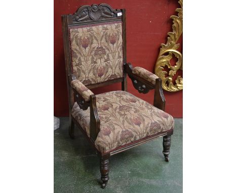 A late Victorian mahogany salon armchair, cupid's bow carved top rail, padded back, open arms, stuffed over seat, turned fore