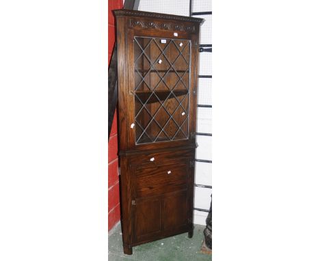 A Jaycee oak corner cupboard, lunette carved frieze, leaded glazed door to top, panel door to base.