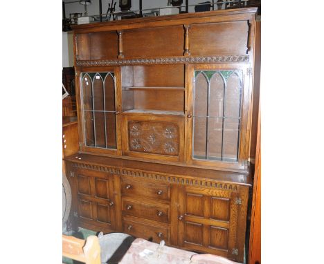 A Priory style oak dresser, recess over shelving, fall front cabinet and glazed door cupboards to top, three drawers flanked 