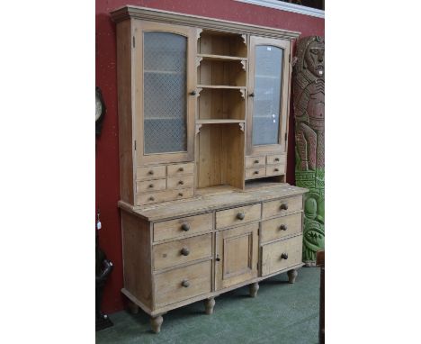 A stripped pine dresser,ogee cornice, shelves flanked by glazed cupboards and drawers to top, panel doored cupboard and an ar