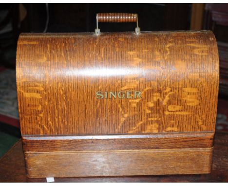 A manual Singer sewing machine, arched oak case, carry handle