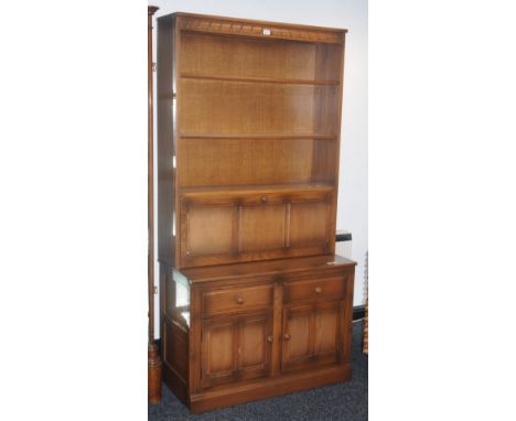 An Ercol light oak display cabinet, two glazed doors over recess to top, two panel door to base; another, shelving over fall 