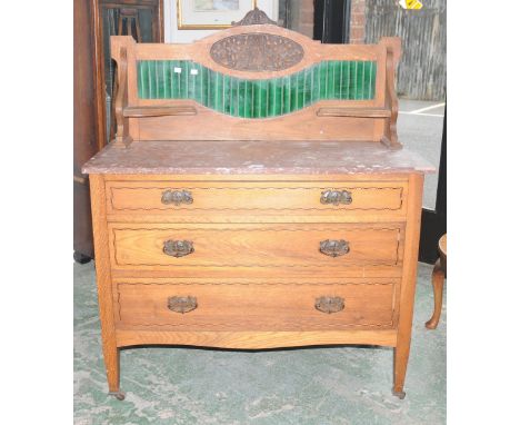 An oak Art Nouveau washstand, tile back, rouge marble top, three graduated drawers to base, tapering square legs, ceramic cas
