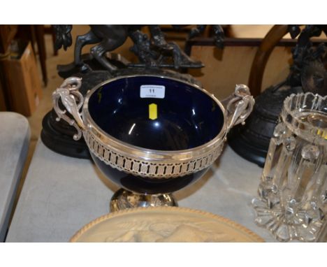 A silver plated and blue glass lined pedestal twin handled bowl with bird head decoration 