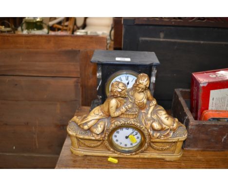 A late Victorian black slate mantel clock  AF; and a plaster mantel clock mounted with two figures 