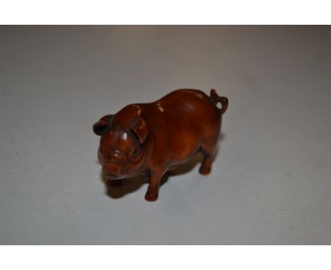 A carved wooden Japanese Netsuke in the form of a pig; signed