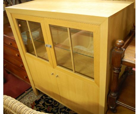 A contemporary light oak four door side cupboard having glazed upper doors