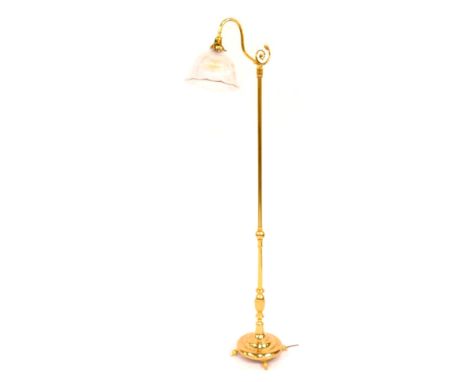 A 20thC brass standard lamp, with a moulded glass ribbed circular tapering shade, on stepped circular base, on three ball fee