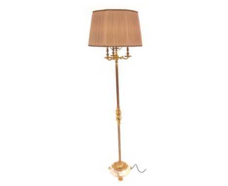 A 20thC brass three branch standard lamp, with a reeded cylindrical column embellished with ornate scroll motifs, on a circul