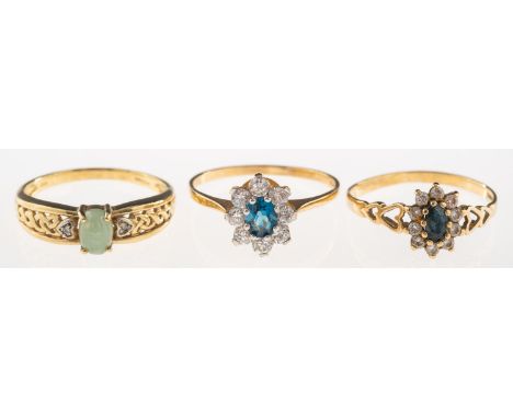A group of three 9ct gold rings, including a cluster ring set with a central oval-cut blue stone with a surround of circular-