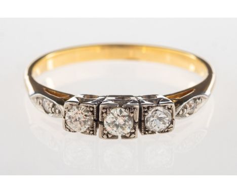 An Art Deco three stone diamond ring, set with three older-cut diamonds in a square setting, with a single-cut diamond set ea