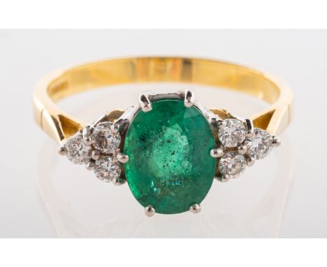 An 18ct gold emerald and diamond ring, claw set to the centre with an oval-cut emerald, with a trefoil of diamonds to each si
