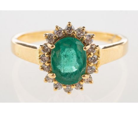 An emerald and diamond cluster ring, claw set to the centre with an oval-cut emerald, with a surround of brilliant-cut diamon