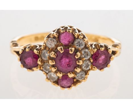 An 18ct gold ruby and diamond cluster ring, set to the centre with a line of three circular-cut rubies with four small brilli