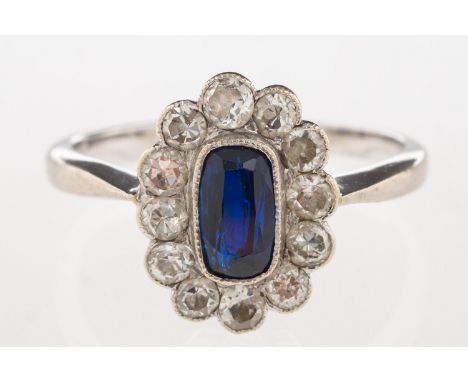 A cluster ring, set to the centre with an elongated oval synthetic sapphire with a surround of single-cut diamonds, marked 18