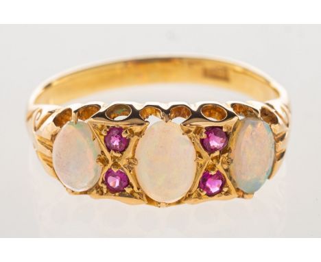 An opal and ruby ring, set with three opal cabochons, interspaced by four circular-cut rubies, carved scroll shoulders, marke