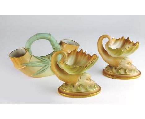 A pair of Royal Worcester blush ivory sweet meat dishes, early 20th century, moulded in the form of dolphins supporting a sca