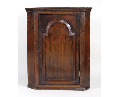 A George III oak wall hanging straight fronted corner cabinet, the single fielded arch panel door opening to reveal three con