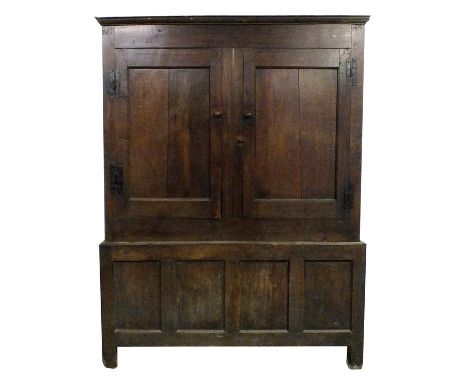 A mid 18th century oak livery cupboard, the two single panel cabinet doors fitted with iron H hinges and turned knob handles,