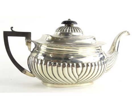 An Edwardian silver teapot, with part fluted decoration, ebonised knop and handle, Birmingham 1905, 11¾ oz gross.