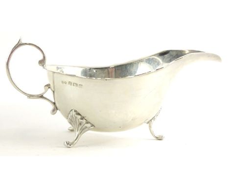 A George V silver sauce boat, with a shaped edge, scroll handle and shaped legs, headed by leaf casting, Birmingham 1920, 4½ 