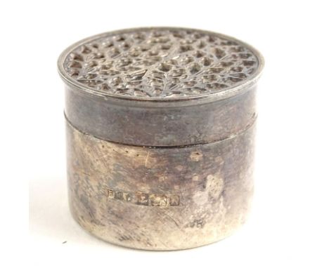 A small silver cylindrical pill box, the lid with a pierced Gothic decoration, on an ebonised background, Birmingham 1984, 3c