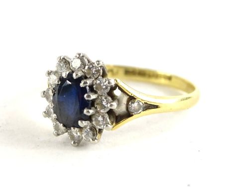 An 18ct gold sapphire and diamond cluster ring, with central oval sapphire surrounded by 12 tiny diamonds, with V shaped shou