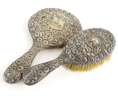 An Edwardian silver hand brush, embossed with flowers, scrolls and leaves, surrounding a vacant cartouche and a matching hand